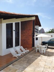 eine Gruppe Stühle und ein Sonnenschirm auf einer Terrasse in der Unterkunft Casa Leonardo in São Luís