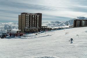 a person skiing down a snow covered slope in front of a building at Departamentos Gran Parador ski In-out de los Centro de Ski El Colorado, Farellones - Descuentos especiales en actividades ski y no ski in Farellones