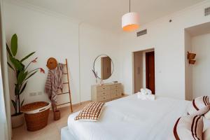 a white bedroom with a bed and a mirror at Voyage One Bedroom In Ansam in Abu Dhabi
