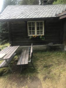 a wooden bench sitting in front of a cabin at Rønlund Hyttepark in Ron
