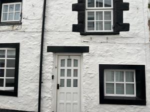 a white building with a white door and three windows at Sweet Cottage in Ingleton