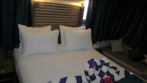 a white bed with white pillows and purple bows on it at Ben's Dahabeya in Aswan