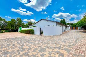 a white house with a brick driveway at Luxurious, spacious & central in Sandton