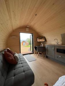 a room with a couch and a kitchen with a table at Willow Farm Glamping in Chester