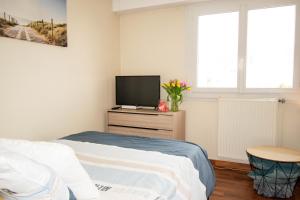 1 dormitorio con cama y vestidor con TV en grand studio avec parking à 10 minutes des plages en Lorient