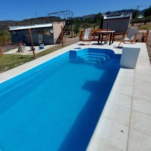 a blue swimming pool with a table and chairs at Balcon al Valle Grande, San Rafael Mendoza in Valle Grande