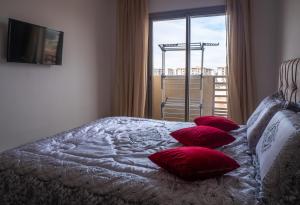 - une chambre avec un lit doté d'oreillers rouges et une fenêtre dans l'établissement Luminous & cosy studio - 5 mins from Mohammed V Airport, à Nouaceur