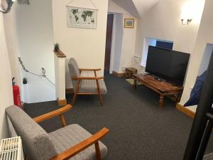 a living room with a tv and a couch and a chair at Sweet Cottage in Ingleton