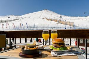 a table with a sandwich and two glasses of beer at Departamentos Gran Parador ski In-out de los Centro de Ski El Colorado, Farellones - Descuentos especiales en actividades ski y no ski in Farellones