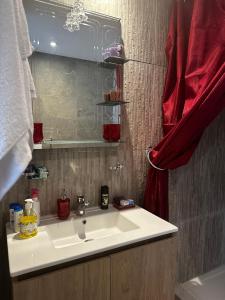 La salle de bains est pourvue d'un lavabo blanc et d'un rideau rouge. dans l'établissement Luminous & cosy studio - 5 mins from Mohammed V Airport, à Nouaceur
