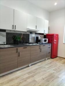 uma cozinha com armários brancos e um frigorífico vermelho em I 23 PASSI SCAURI em Scauri
