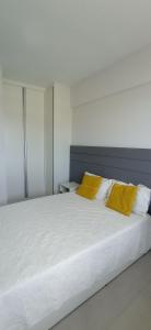 um quarto com uma cama branca e 2 almofadas amarelas em Jaguaribe Praia em Salvador