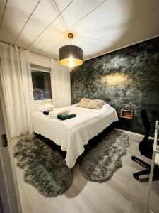 een slaapkamer met een wit bed en een zwart-grijze muur bij Rubin Apartment in Kajaani