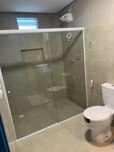 uma casa de banho com uma cabina de duche em vidro e um WC. em KEFI POUSADA em Maragogi