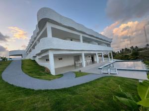 a white house with a swimming pool in the yard at KEFI POUSADA in Maragogi