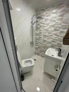 Baño blanco con aseo y lavamanos en Двустаен апартамент за двама., en Burgas