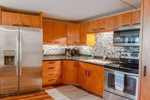 uma cozinha com armários de madeira e electrodomésticos de aço inoxidável em Beachfront Condo with AC em Laie