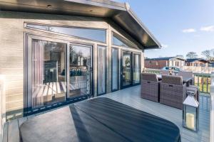 una casa con una gran puerta de cristal en una cubierta en Woodland Jewel Lodge with Hot Tub, en York