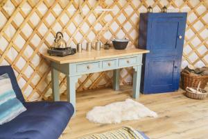 Wilding Yurt Stay في بروتون إن فورنيس: غرفة مع طاولة وباب أزرق في يورت