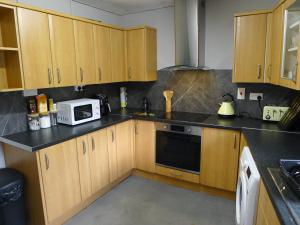 a kitchen with wooden cabinets and a microwave at Saltoun House in Fraserburgh