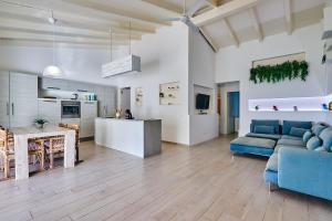 a living room with a blue couch and a kitchen at Beach Villa by Bobbywashere in Santa Maria