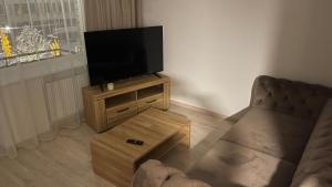 uma sala de estar com uma televisão de ecrã plano num suporte de madeira em Central Boulevard Apartment 2 em Siauliai
