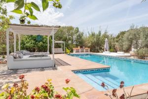 een zwembad met een bank en een pergola naast een zwembad bij 8 Guests Large Villa near Bossa Beaches & Airport in San Jose de sa Talaia