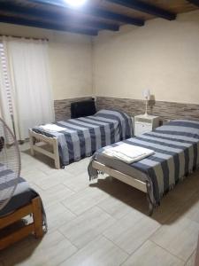 a room with two beds and a chair in it at La Catalina 2 in San Antonio de Areco