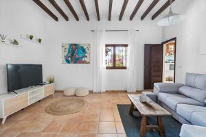 ein Wohnzimmer mit einem blauen Sofa und einem TV in der Unterkunft 8 Guests Large Villa near Bossa Beaches & Airport in San Jose de sa Talaia