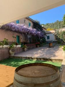 a house with a barrel in a courtyard with purple flowers at Corte Boero Bed&Breakfast in Capoterra