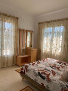 a bedroom with a bed and a mirror and windows at Residence-Sassi in Nabeul