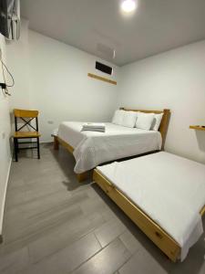 a bedroom with two beds and a chair at Hotel Alameda Plaza in Cali