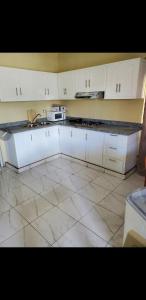 eine Küche mit weißen Schränken und Fliesenboden in der Unterkunft July in San Felipe de Puerto Plata