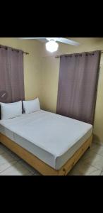 ein großes Bett in einem Zimmer mit zwei Fenstern in der Unterkunft July in San Felipe de Puerto Plata