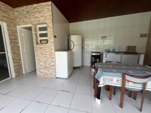 une cuisine avec une table et un réfrigérateur dans l'établissement Casa aconchegante a 5min a pé da praia de Boracéia!, à Boraceia 2 autres photos