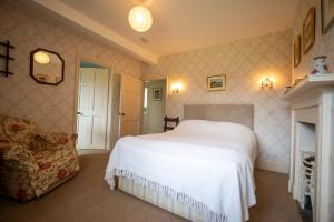 Un dormitorio con una cama blanca y una silla. en Garden House, en North Lydbury