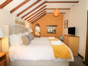 a bedroom with a large white bed and a television at King's Cottage in Bedale