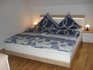 a bed with blue and white sheets and pillows at Ferienhaus Lachmöwe in Fehmarn
