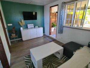 una sala de estar con una mesa blanca y un sofá en Fare Miti-Rapa climatisation, baignoire et qualité pour votre confort, en Tohautu