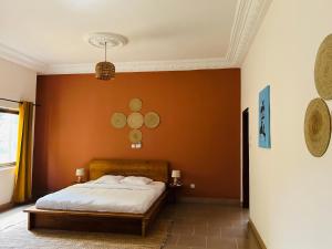a bedroom with a bed with orange walls at Cocoon Guest House in Cotonou