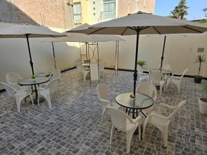 un patio con mesas, sillas y sombrillas en Pacific Suites Hotel, en Tacna