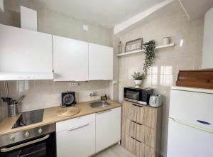 uma cozinha com armários brancos, um lavatório e um micro-ondas em Casa Alfocea em Caravaca de la Cruz