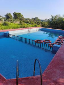 a swimming pool with chairs and a swing at Gokul farm house in Sasan Gir
