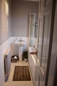 La salle de bains blanche est pourvue d'un lavabo et d'un miroir. dans l'établissement Amazing 2-Bed Home w/ Private Garden Free Parking, à Cardonald