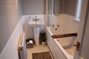 a bathroom with a sink and a bath tub with a sink at Amazing 2-Bed Home w/ Private Garden Free Parking in Cardonald