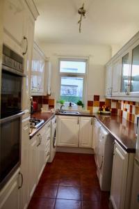 une grande cuisine avec des placards blancs et une fenêtre dans l'établissement Amazing 2-Bed Home w/ Private Garden Free Parking, à Cardonald