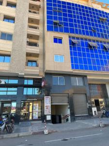 a tall building with blue glass windows on a street at Apartement Boulevard Mohammed Derfoufi Oujda in Oujda