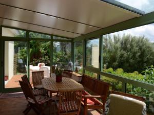 a screened in porch with a table and chairs at Villa Finistère proche plage in PloÃ©ven