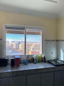 a kitchen counter with a view of a city from a window at Apartement Boulevard Mohammed Derfoufi Oujda in Oujda