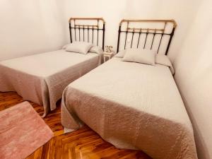 two twin beds in a room with wooden floors at La Cava de Leuvino Frias 